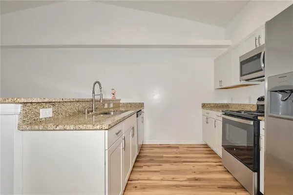 a kitchen with stainless steel appliances granite countertop a stove microwave and refrigerator