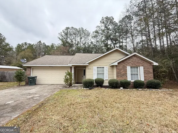 a front view of a house with yard and trees in the background