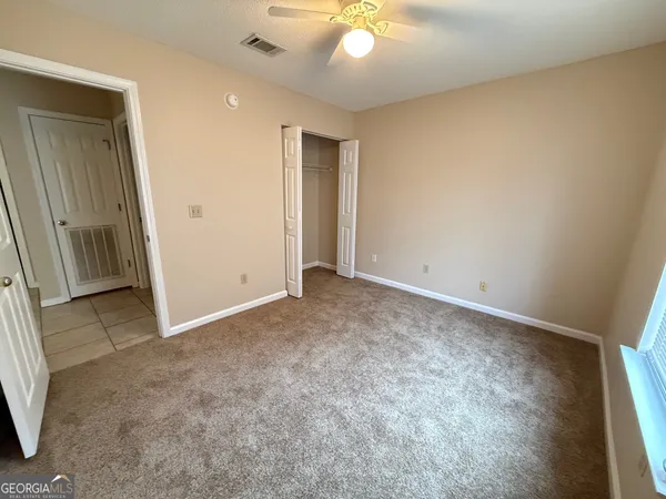 an empty room with a chandelier fan and windows