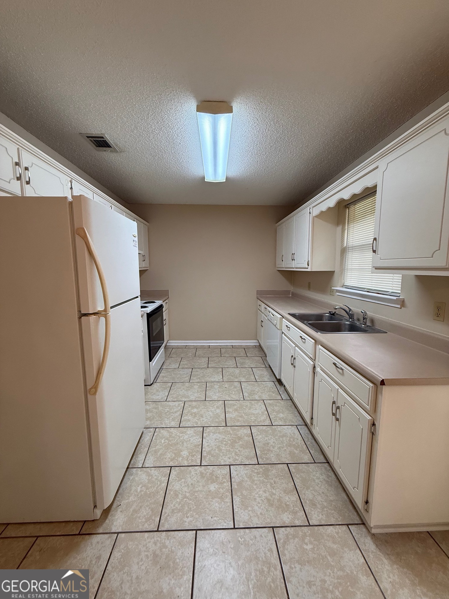 504 Woodbridge Road Kingsland, GA 31548 - Photo 5 of 23 a kitchen with white cabinets a sink a stove and a refrigerator