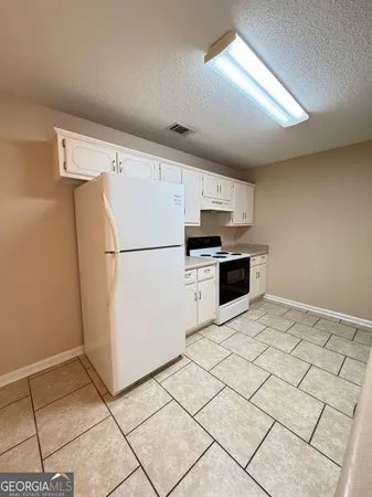 a kitchen with granite countertop a refrigerator and a stove top oven