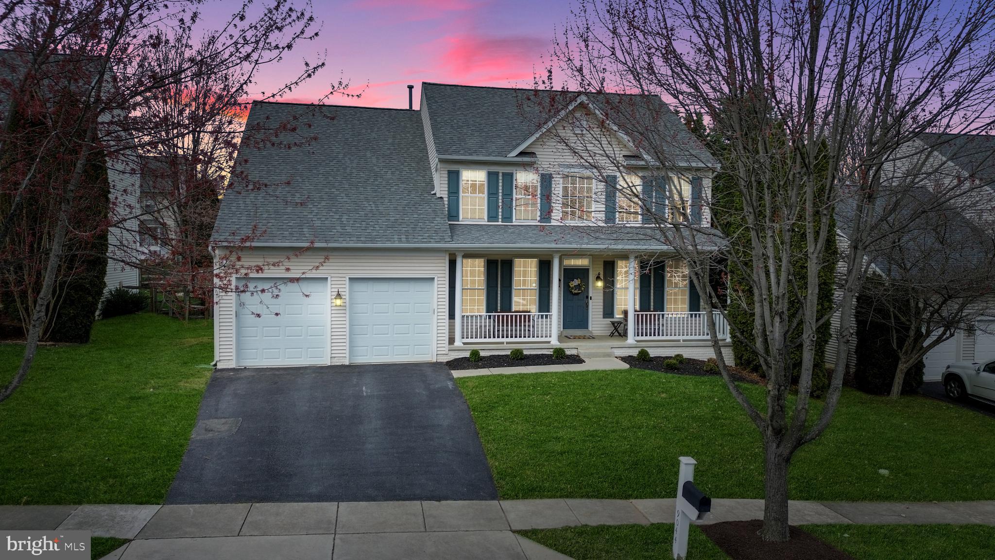 a front view of a house with a garden and trees