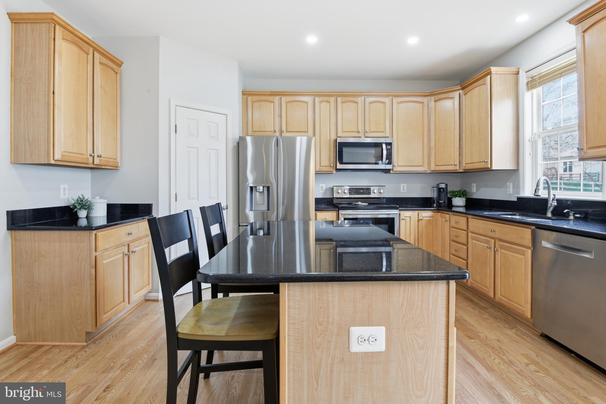 9044 Clendenin Way Frederick, MD 21704 - Photo 4 of 50 a kitchen with stainless steel appliances granite countertop a refrigerator a stove a sink a dining table and chairs with wooden floor