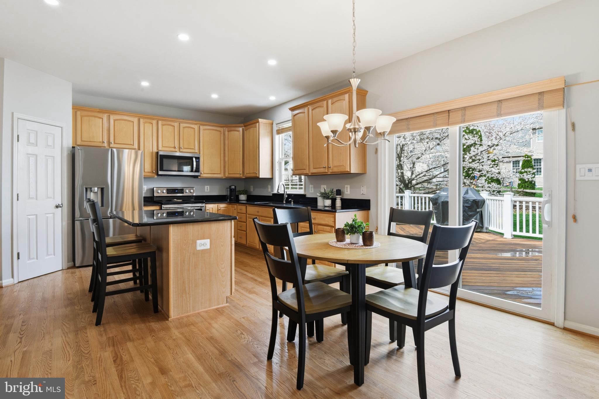 9044 Clendenin Way Frederick, MD 21704 - Photo 6 of 50 a kitchen with stainless steel appliances granite countertop a stove a refrigerator a microwave a dining table and chairs with wooden floor