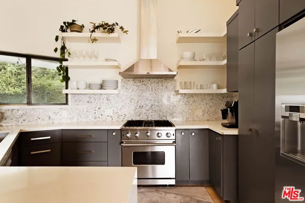 a kitchen with granite countertop a stove and white cabinets with wooden floor
