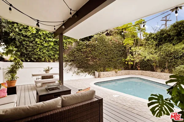 a view of a patio with couches table and chairs with wooden floor and fence