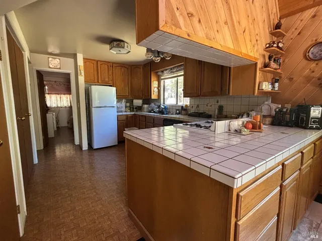 a kitchen with stainless steel appliances granite countertop a sink a stove a refrigerator a washer and dryer