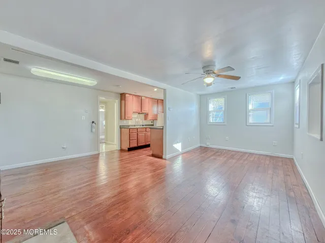 an empty room with wooden floor cabinet and windows