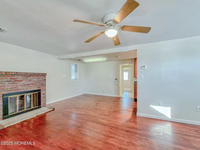 a view of an empty room with wooden floor and a fireplace