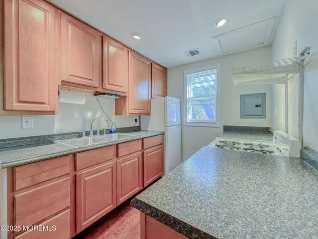 a kitchen with stainless steel appliances granite countertop a sink and cabinets with wooden floor