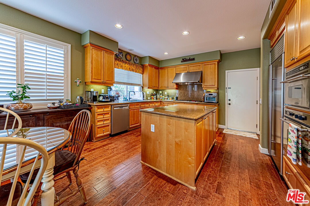23208 Maple Avenue Torrance, CA 90505 - Photo 14 of 62 a kitchen with stainless steel appliances granite countertop wooden floors a stove a sink a dining table and chairs