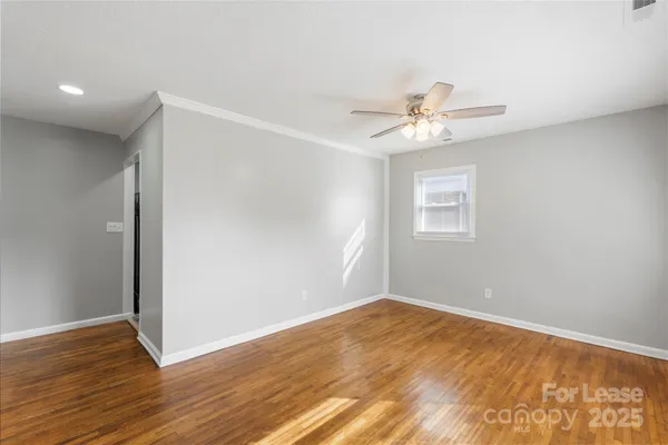 a view of a room with wooden floor and a ceiling fan
