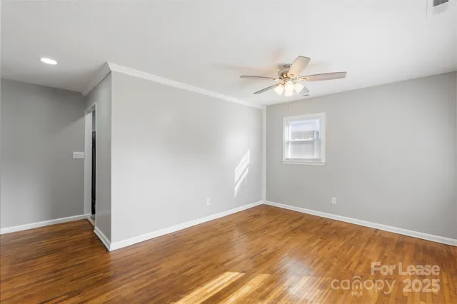 a view of a room with wooden floor and a ceiling fan