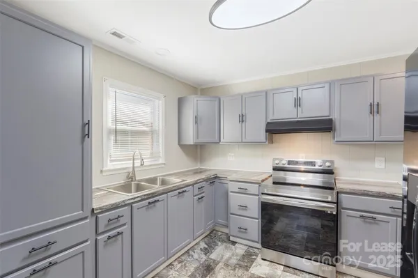 a kitchen with granite countertop a stove sink and cabinets