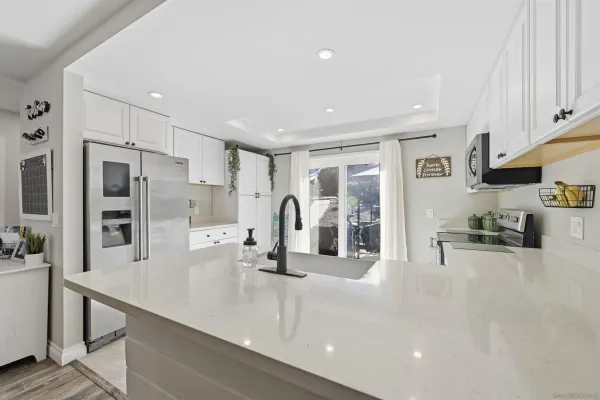 a kitchen with stainless steel appliances a sink a stove and white cabinets
