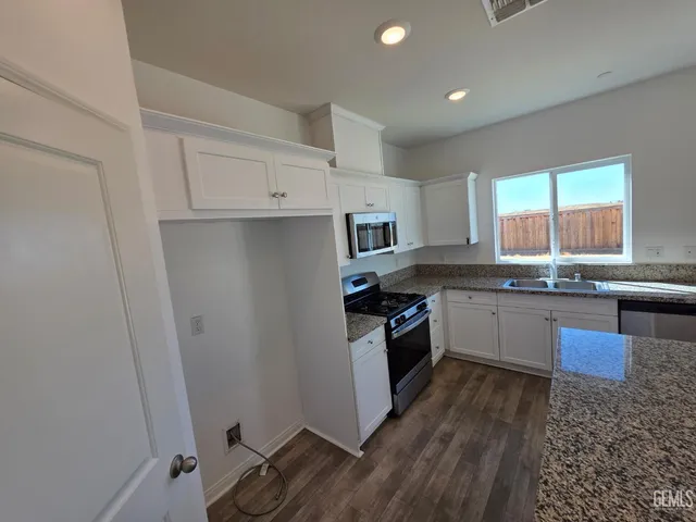 a kitchen with granite countertop a refrigerator a sink a stove a microwave and island