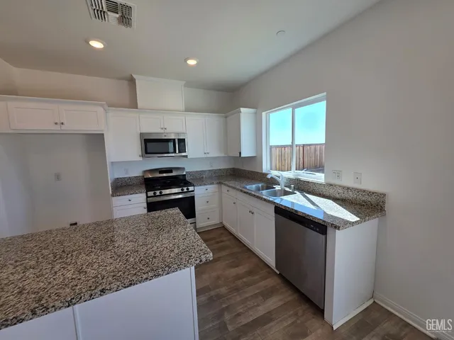 a kitchen with granite countertop a sink and steel appliances