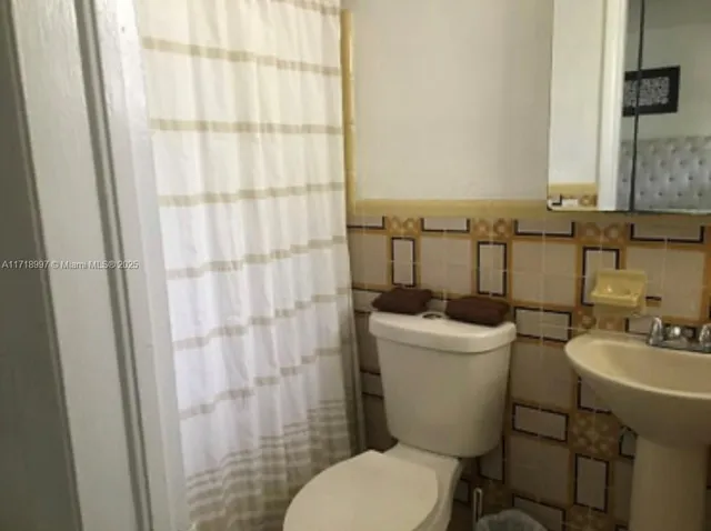 a bathroom with a sink a toilet a mirror and shower curtain