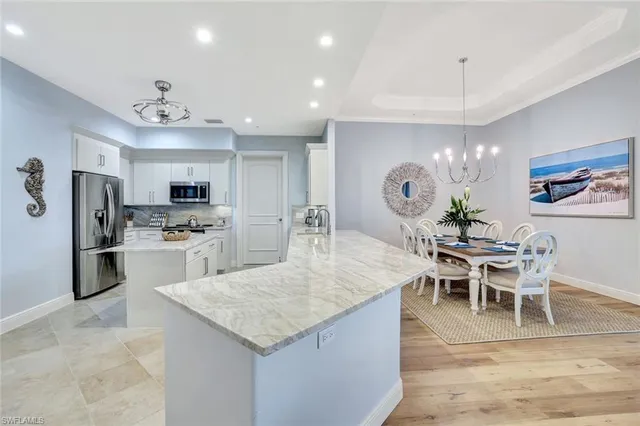 a kitchen with stainless steel appliances kitchen island a refrigerator a stove a dining table and chairs with wooden floor