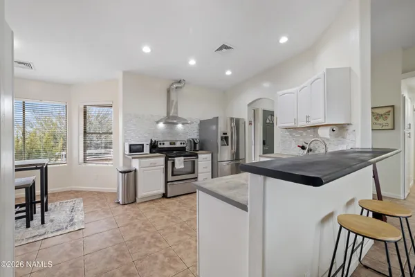 a large kitchen with granite countertop a large counter top space appliances and cabinets