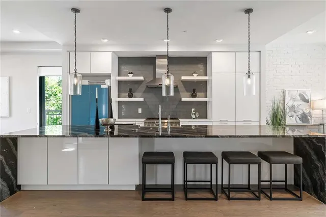 a kitchen with stainless steel appliances granite countertop a refrigerator a stove a sink and a dining table with wooden floor