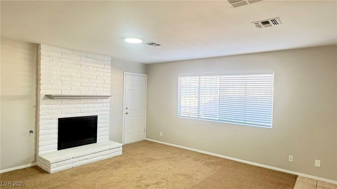 7113 Pinelake Road Las Vegas, NV 89145 - Photo 6 of 22 Unfurnished living room with a brick fireplace and light colored carpet