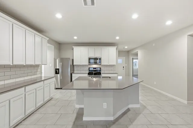 a large kitchen with kitchen island a sink stainless steel appliances and cabinets