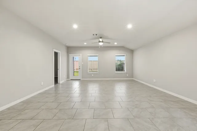 an empty room with windows and fan