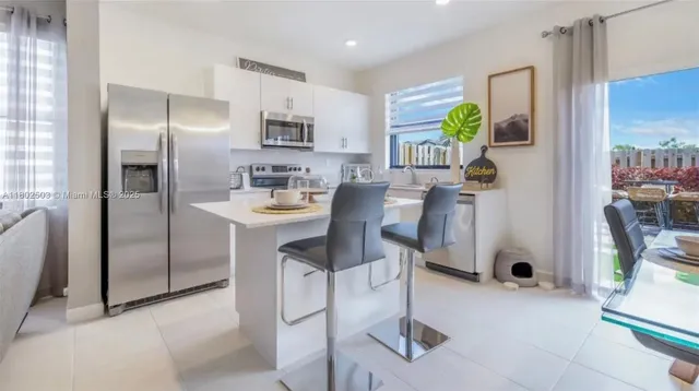 a kitchen with stainless steel appliances granite countertop a refrigerator a stove a sink a dining table and chairs