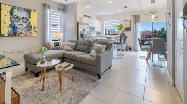 a living room with couches a coffee table and kitchen view with wooden floor