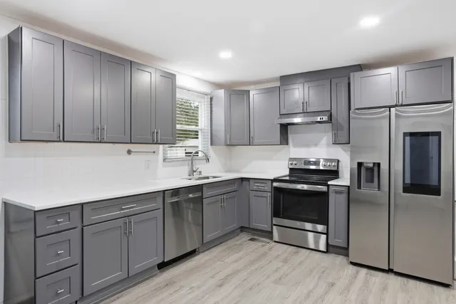 a kitchen with stainless steel appliances granite countertop a stove a sink and a refrigerator