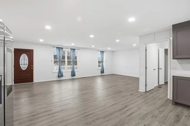 a view of an empty room with a window and wooden floor