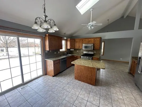 a large kitchen with stainless steel appliances granite countertop a stove center island a refrigerator and a view of living room