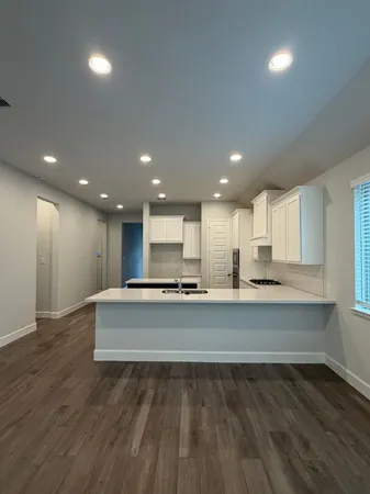 a living room with couches and kitchen view with wooden floor