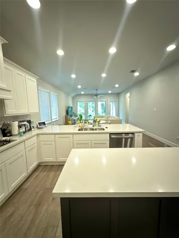 a kitchen with a sink dishwasher stove and white cabinets with wooden floor