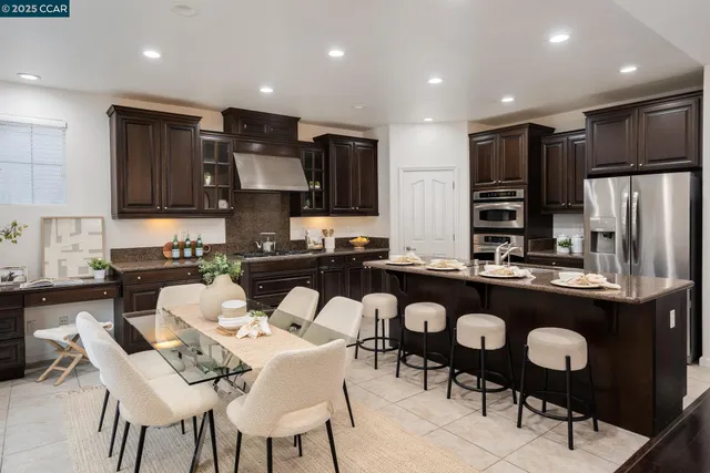 a kitchen with stainless steel appliances kitchen island granite countertop a table and chairs