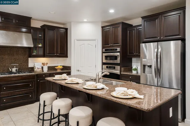 a kitchen with stainless steel appliances granite countertop a sink refrigerator and cabinets