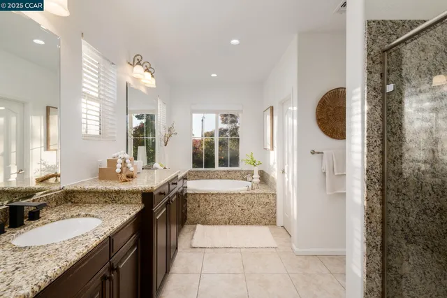 a bathroom with a granite countertop sink a mirror and shower