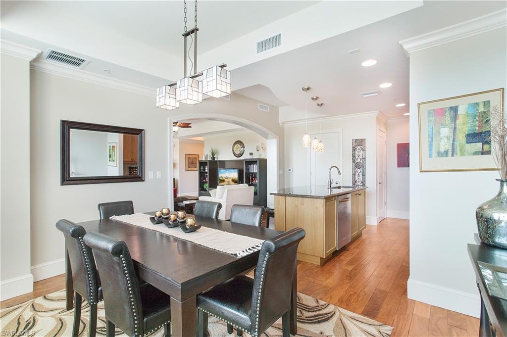 9123 Strada Place, Unit 7307 Naples, FL 34108 - Photo 13 of 49 a view of a dining room with furniture a chandelier and wooden floor