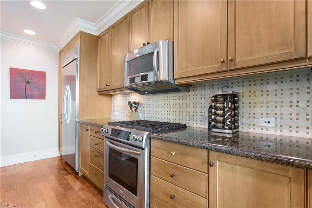 9123 Strada Place, Unit 7307 Naples, FL 34108 - Photo 16 of 49 a kitchen with stainless steel appliances granite countertop a stove a sink and a microwave
