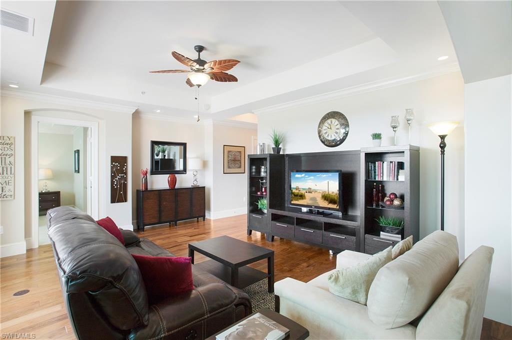 9123 Strada Place, Unit 7307 Naples, FL 34108 - Photo 18 of 49 a living room with furniture a clock and a flat screen tv