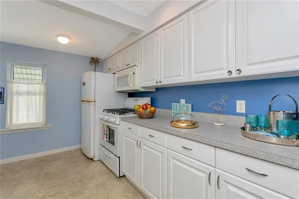 a kitchen with stainless steel appliances granite countertop a sink a stove and a white cabinets