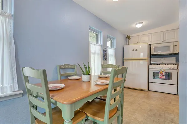 a kitchen with stainless steel appliances granite countertop a dining table chairs and a refrigerator