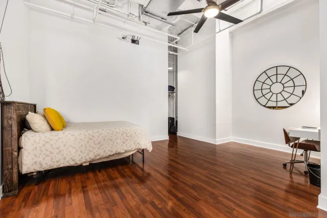 a bedroom with a bed a table and wooden floor