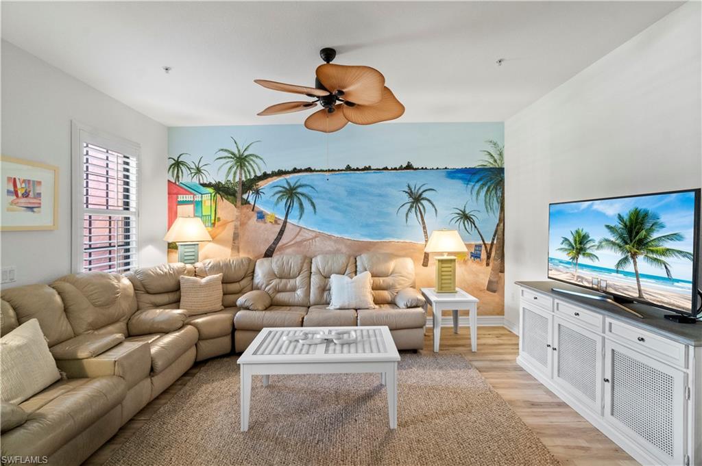 9111 Capistrano Street South, Unit 8303 Naples, FL 34113 - Photo 2 of 29 a living room with furniture a chandelier and a flat screen tv