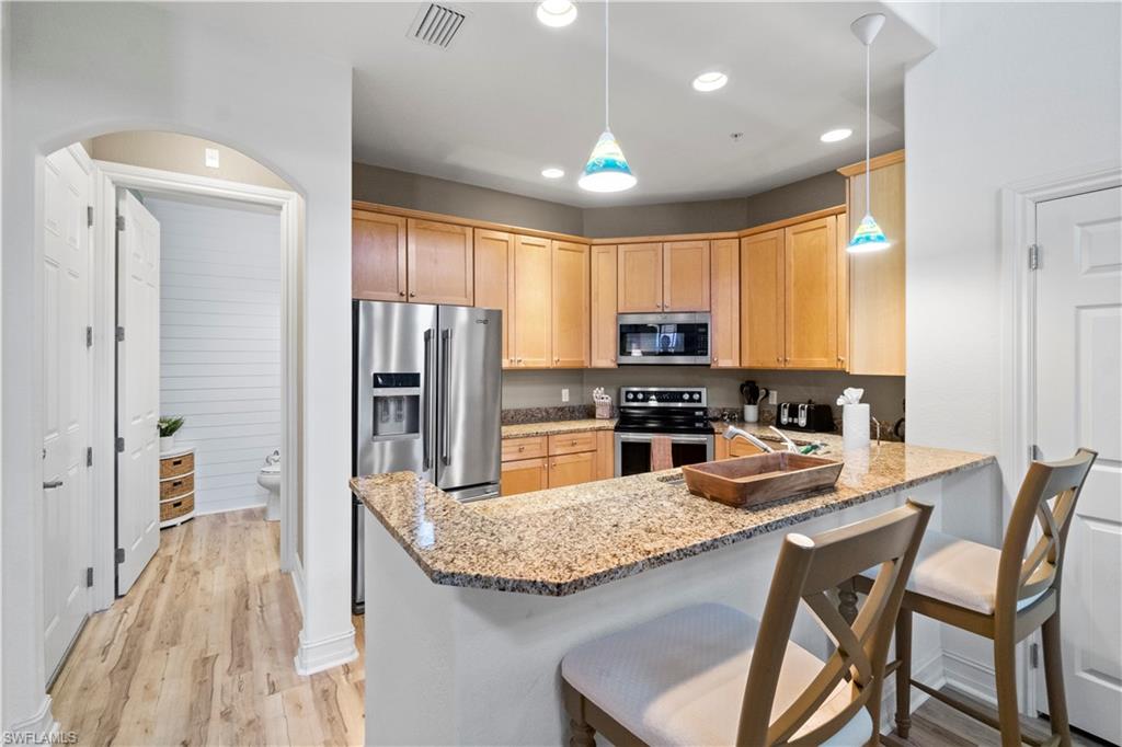 9111 Capistrano Street South, Unit 8303 Naples, FL 34113 - Photo 5 of 29 a kitchen with stainless steel appliances granite countertop a stove refrigerator and a sink