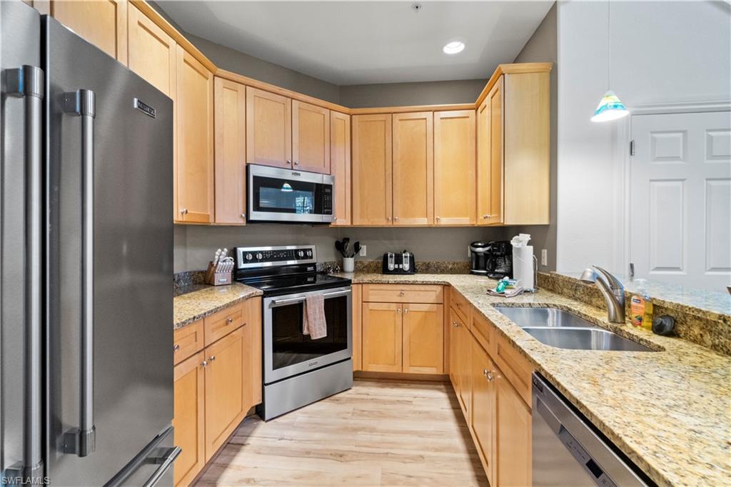 9111 Capistrano Street South, Unit 8303 Naples, FL 34113 - Photo 6 of 29 a kitchen with granite countertop a sink stove and refrigerator