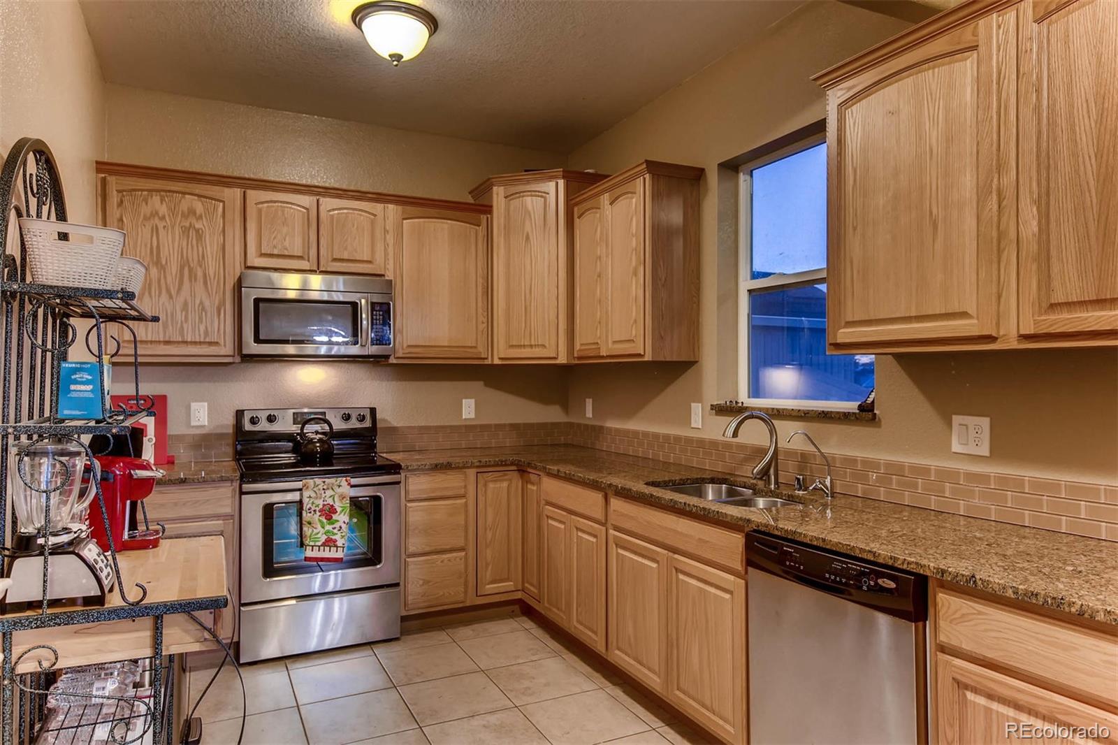 691 Picadilly Road Aurora, CO 80018 - Photo 16 of 27 a kitchen with stainless steel appliances granite countertop a sink stove and microwave