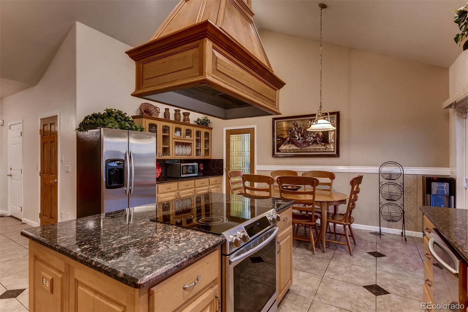 691 Picadilly Road Aurora, CO 80018 - Photo 7 of 27 a kitchen with stainless steel appliances kitchen island granite countertop a stove a refrigerator and a microwave