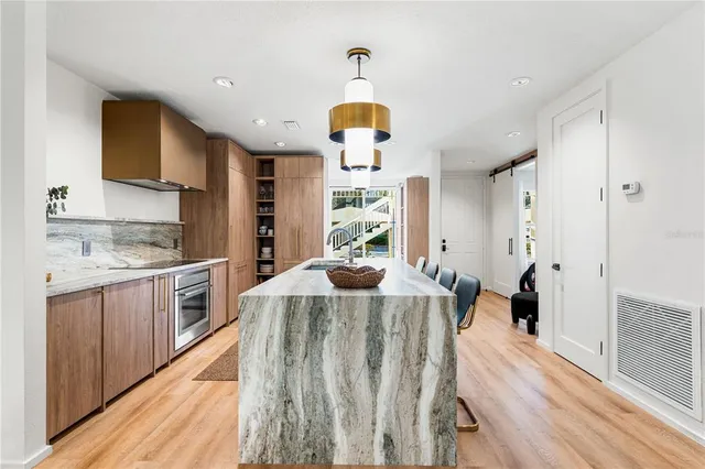 a kitchen with stainless steel appliances granite countertop a stove a sink dishwasher and a refrigerator with wooden floor